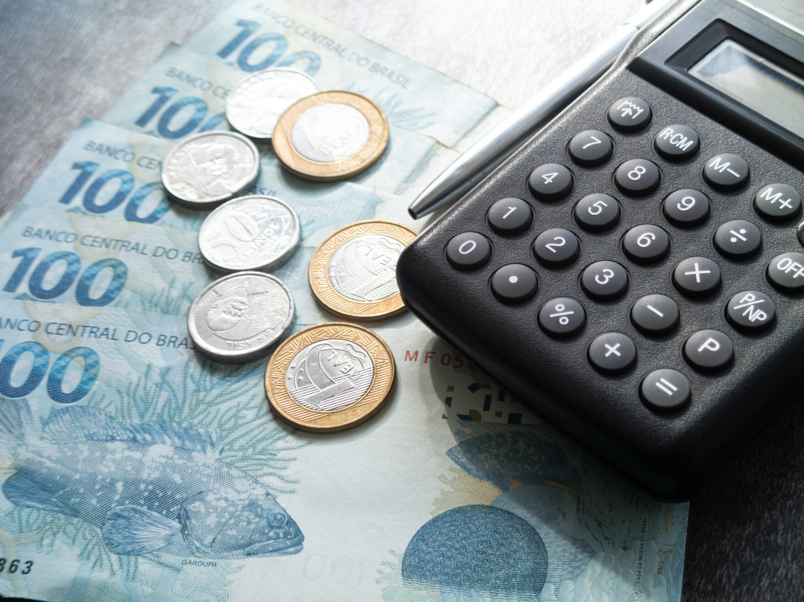 Finance concept one hundred reais bills and coins with calculator and pen brazilian money.